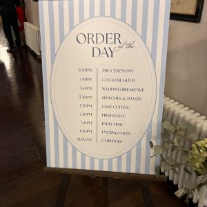 Printed wedding order of the day sign on an easel