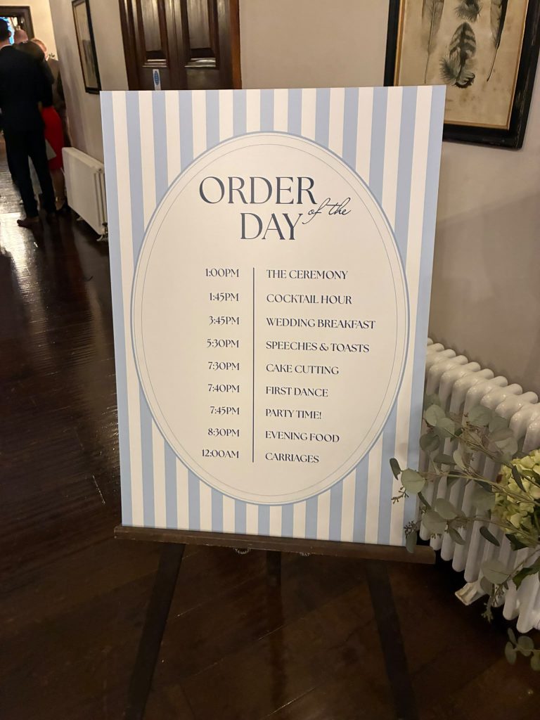 Printed wedding order of the day sign on an easel